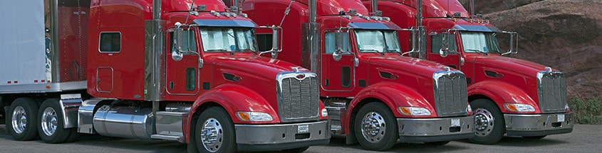 Three red semi trucks parked next to each other | improve CSA scores