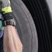 A driver leans against his truck tire as he takes a break | Rising Insurance Premiums for Transportation Firms